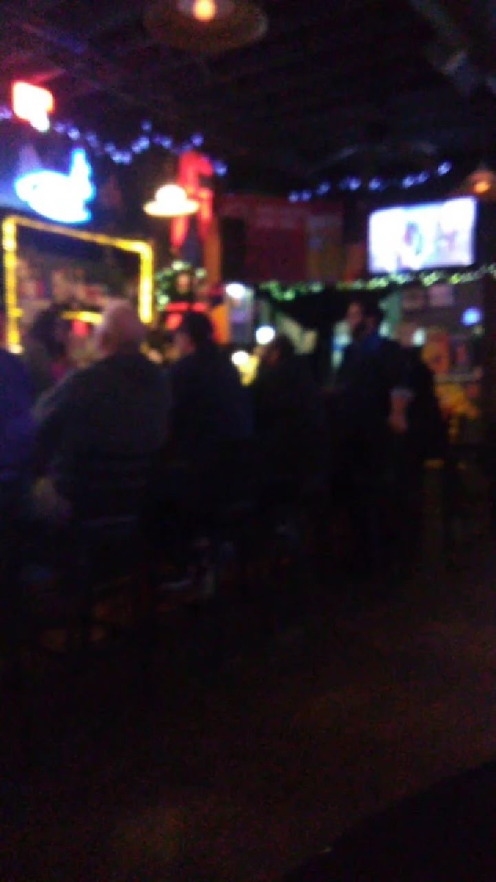 Dimly lit bar with patrons and neon lights.