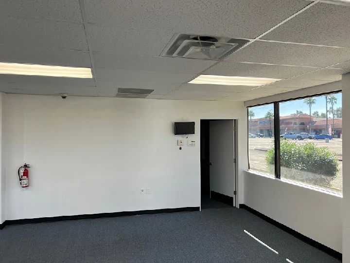 Empty office space with windows and a fire extinguisher.