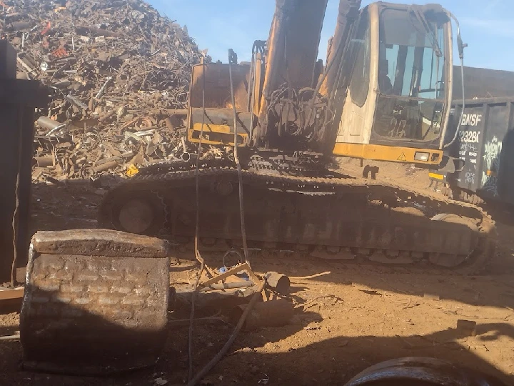 Excavator near a large pile of scrap metal.