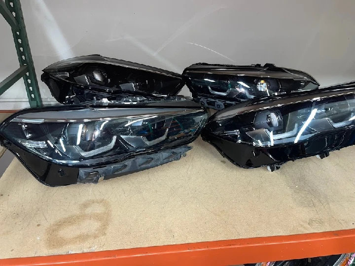 Four black car headlights on a workbench.