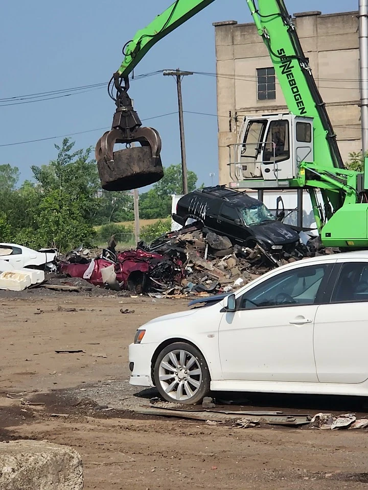 Heavy machinery operates in an auto parts yard.