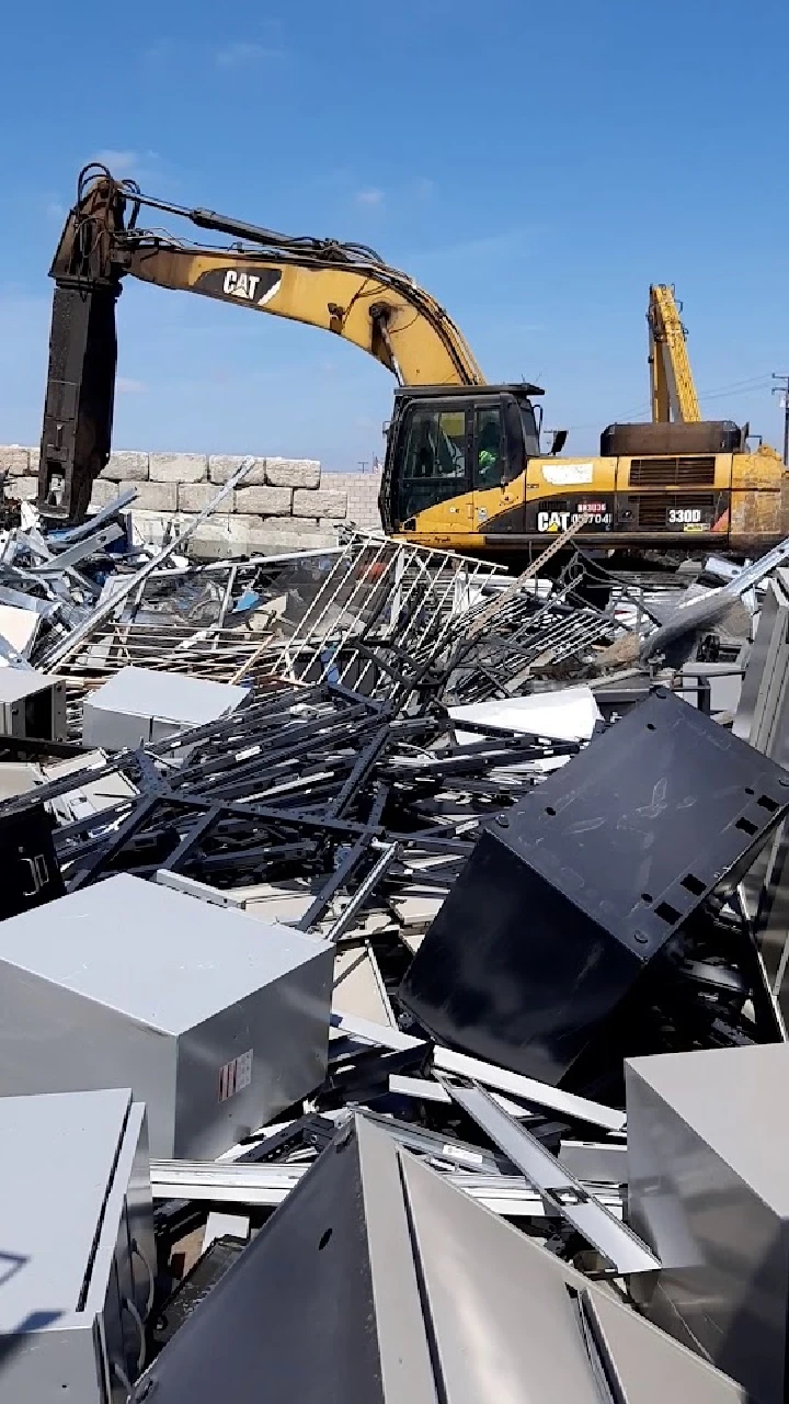 Heavy machinery sorting scrap metal at a recycling site.