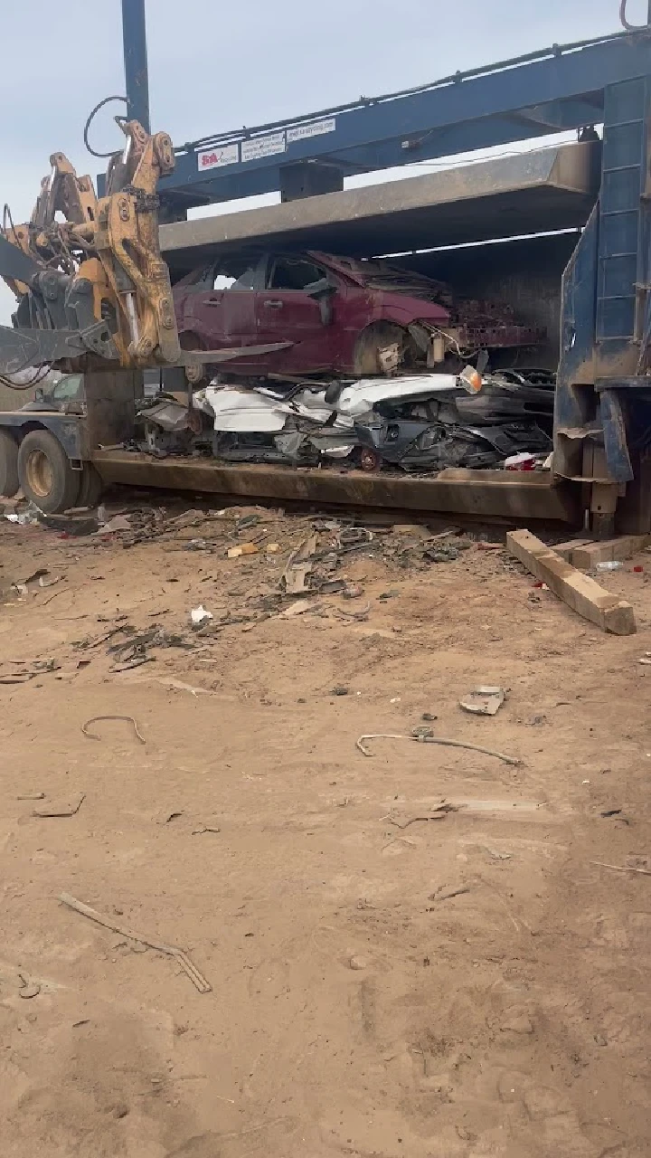 Junk cars being loaded for recycling at a yard.