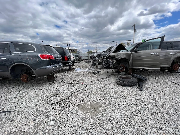 Junkyard with scattered used cars and auto parts.