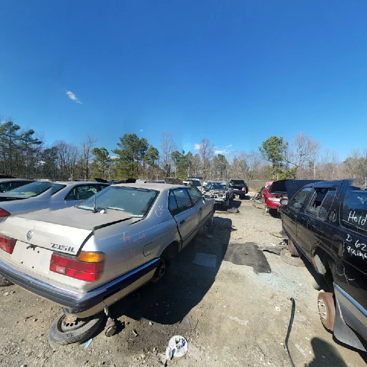 Junkyard scene with abandoned vehicles and blue sky.