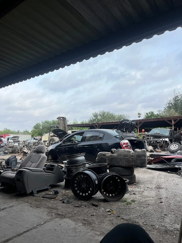 Junkyard view with cars and parts for sale.