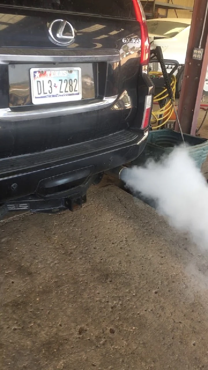 Lexus SUV with exhaust smoke in a garage.