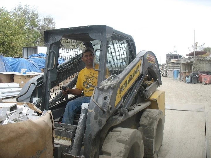 Man operating a skid steer at an industrial site.