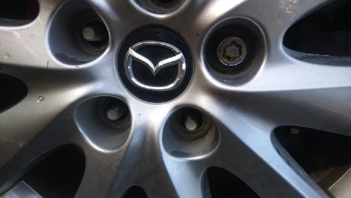 Mazda wheel rim with logo and lug nut detail.