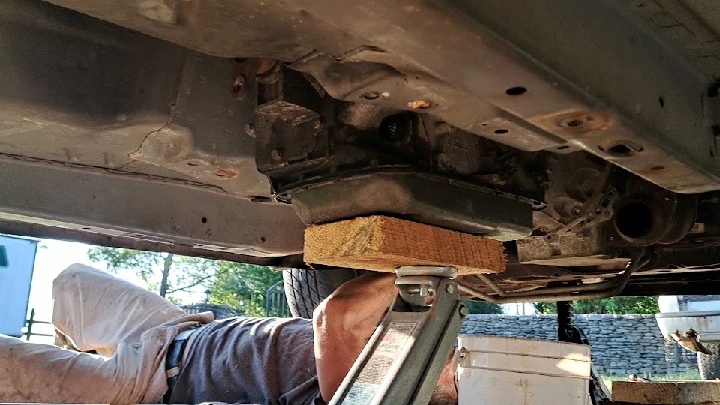 Mechanic working under a vehicle with tools nearby.