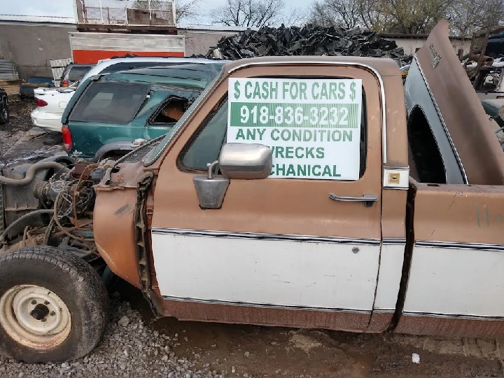 Old truck with cash for cars sign at salvage yard.