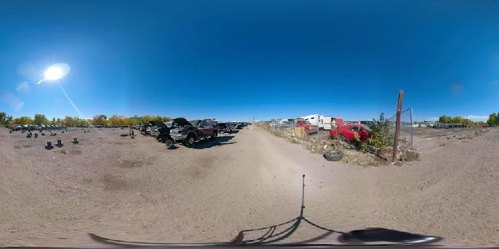 Outdoor junkyard with vehicles under a clear sky.