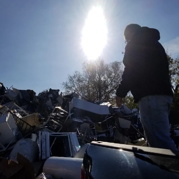 Person standing near a large pile of metal debris.