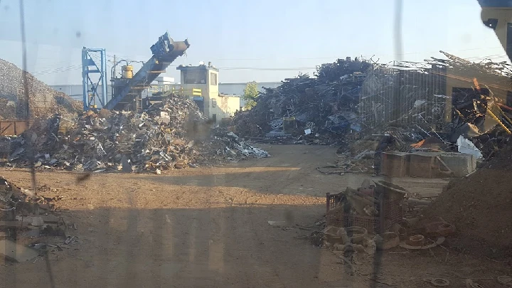 Recycling yard with piles of scrap metal and machinery.