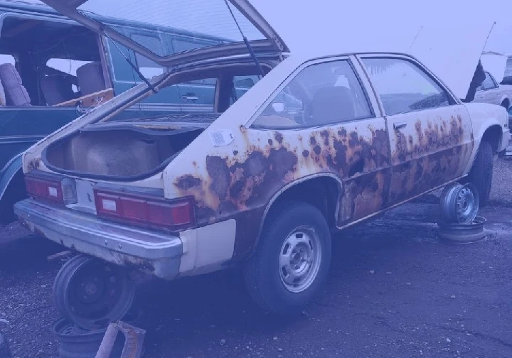 Rusty junk car at a salvage yard for cash deals.