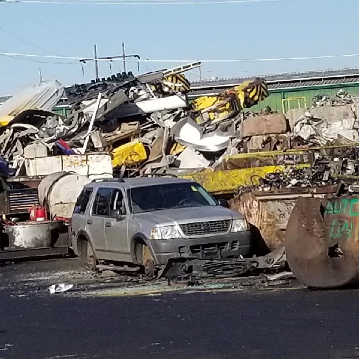 Scrap yard with piles of metal and an old vehicle.