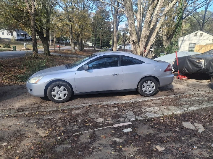 Silver coupe parked on a gravel driveway.