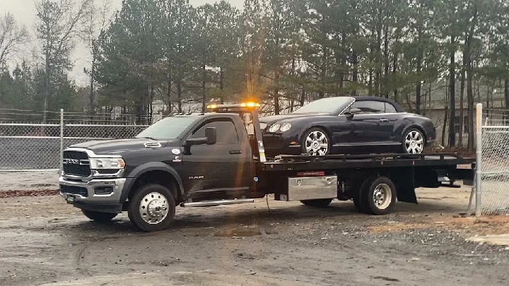 Tow truck carrying a luxury vehicle for junk removal.