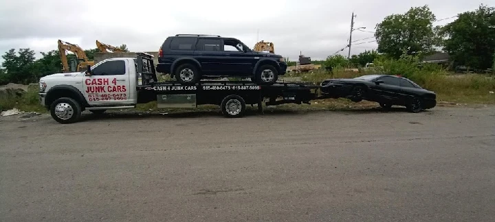 Tow truck carrying two vehicles for junk removal.