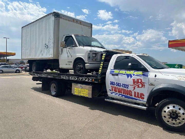 Tow truck carrying a van for junk car service.