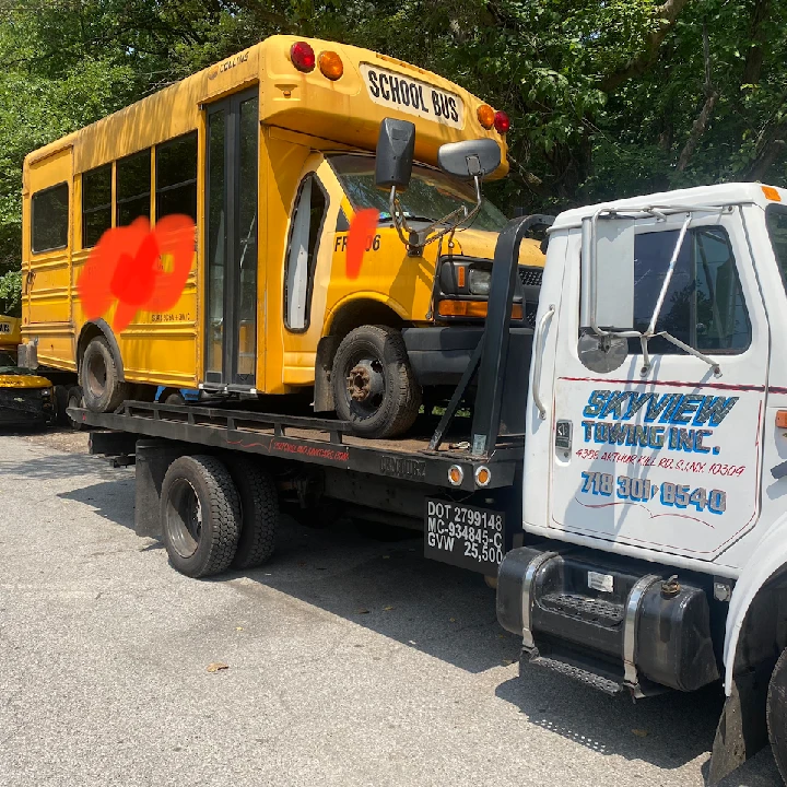 Tow truck carrying a yellow school bus.