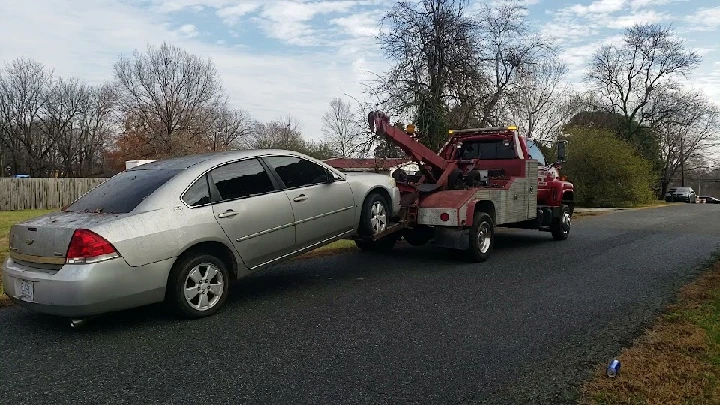 Tow truck removing a junk car from the street.