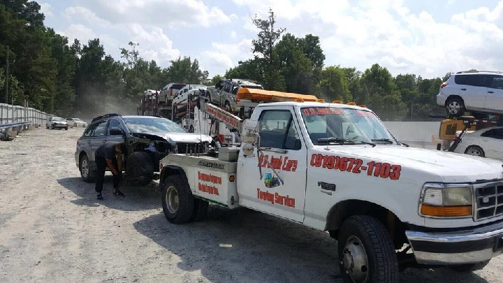 Tow truck servicing a vehicle at a junkyard.