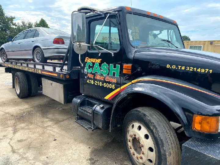 Tow truck transporting a junk car for cash removal.