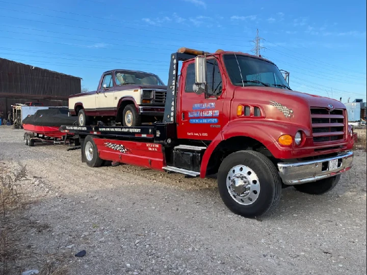 Tow truck with vehicle and boat on flatbed.