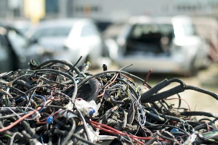 Wires and cables piled at a junk car lot.