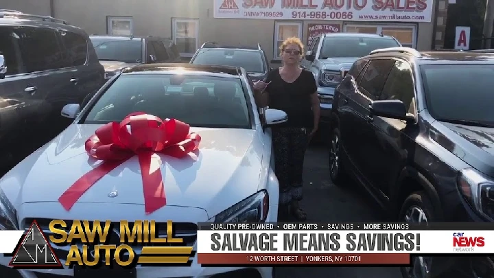 Woman next to a car with a bow at Saw Mill Auto.