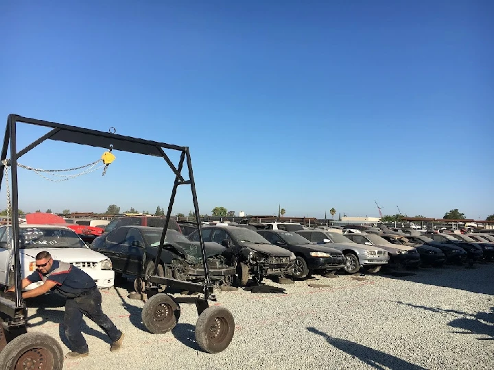 Worker using a hoist in an auto parts yard.