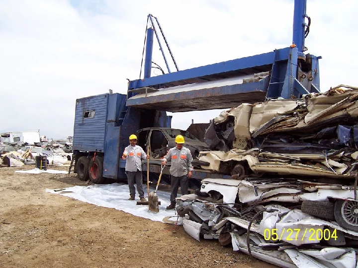 Workers at a recycling facility with crushed cars.