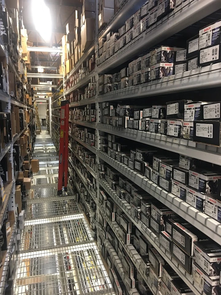 Auto parts warehouse aisle with stacked boxes.