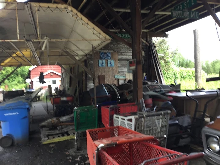 Cluttered garage filled with auto parts and carts.