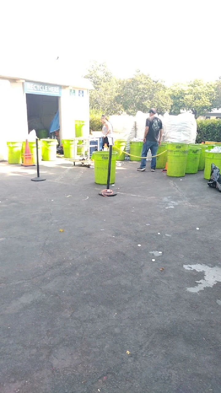 Recycling center with green bins and workers.