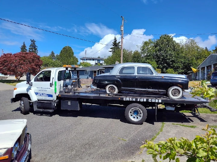 Tow truck transporting a vintage junk car.