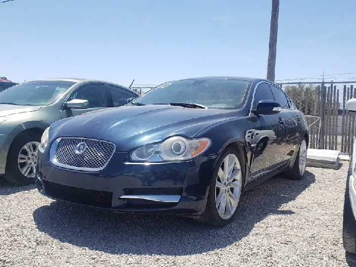 Blue Jaguar sedan parked in a salvage yard.