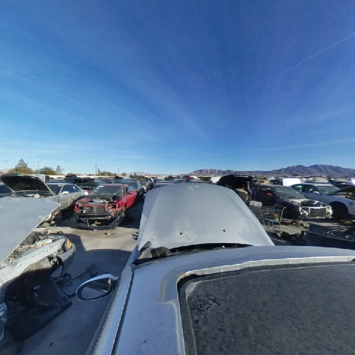 Junkyard full of cars under a clear blue sky.