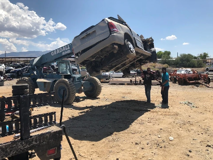 Men lifting a junk car with machinery.