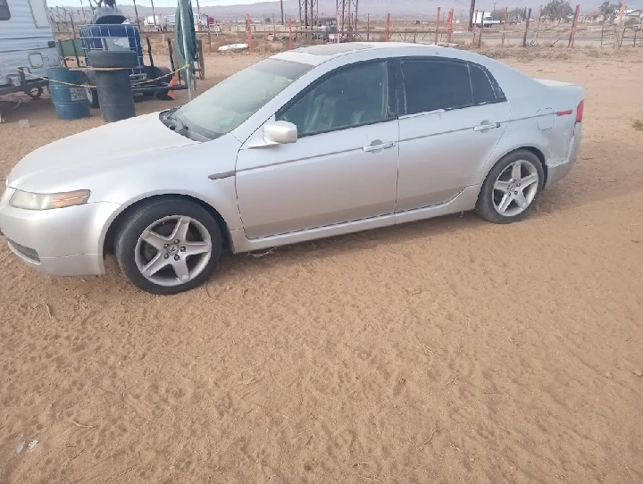 Silver car parked on a sandy surface.